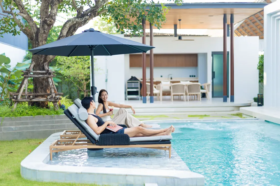 AVANA villa: two guests on sun loungers beside the pool