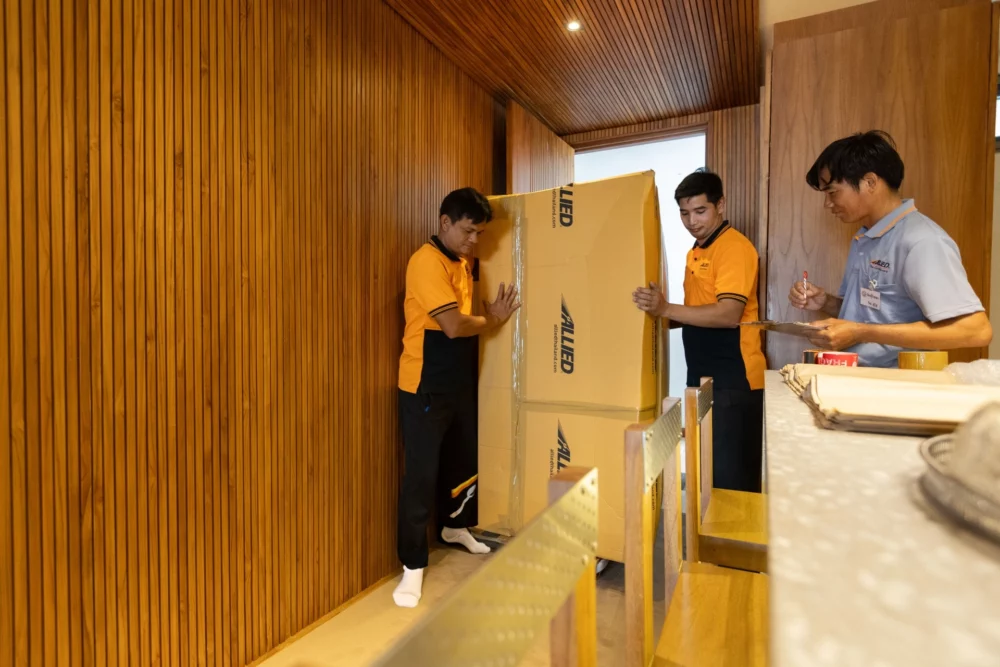 Movers carrying a boxed item through a timber-panelled hallway
